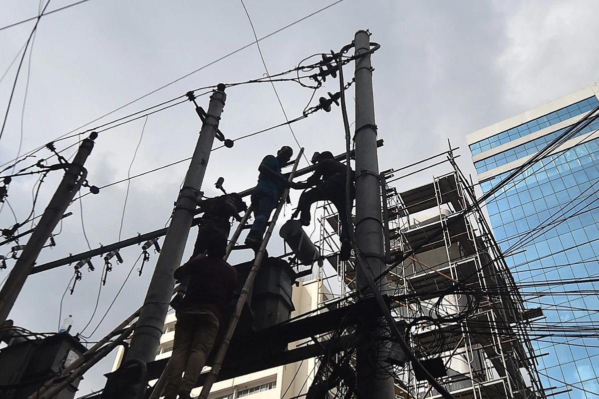 Workers repair an electrical transformer in Dhaka, Bangladesh, on June 13, 2021. (AFP)