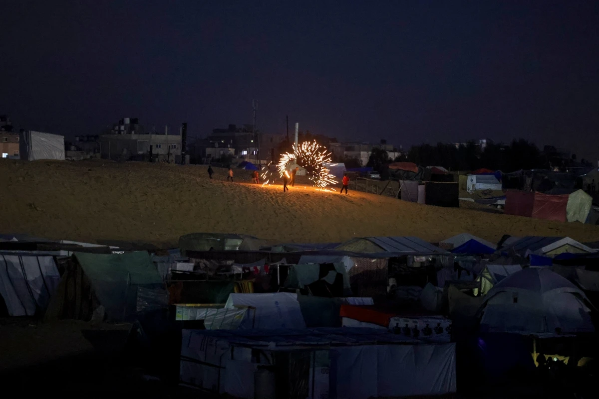Children play with sparklers at a camp for displaced Palestinians in Rafah on the eve of Ramadan. Mar. 10, 2024 (AFP)