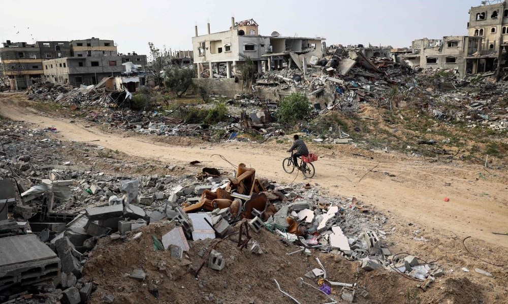 A cyclist passes damaged buildings in Khan Younis, after Israel pulled its forces out of southern Gaza, Apr. 8, 2024. (AFP)
