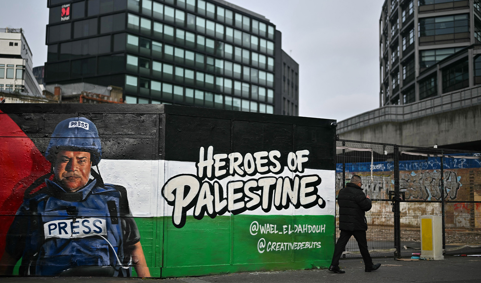 A pedestrian walks past a graffiti made by Spanish street artist Nacho Welles, also known as Core246, depicting Palestinian journalist and bureau chief of Al Jazeera in Gaza City Wael al-Dahdouh, as part of a project launched by the art platform Creative Debuts called "Heroes of Palestine", in east London, on January 29, 2024. (AFP/File)