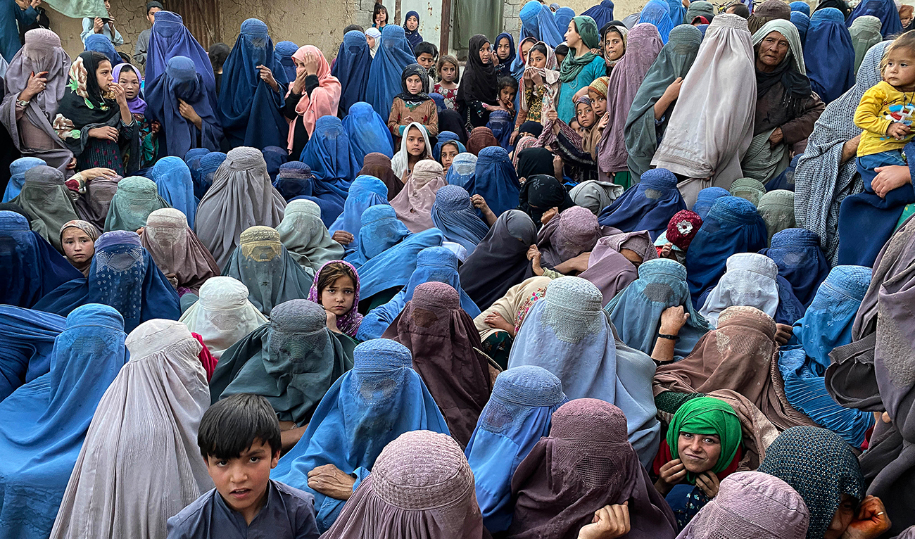 Afghan burqa-clad women wait to receive free food from a local charity during the Islamic holy fasting month of Ramadan in Kandahar on April 2, 2024. (AFP)