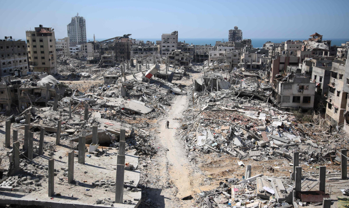 A man pushes a bycicle along as he walks amid building rubble in the devastated area around Gaza's Al-Shifa hospital on April 3, 2024. (AFP)