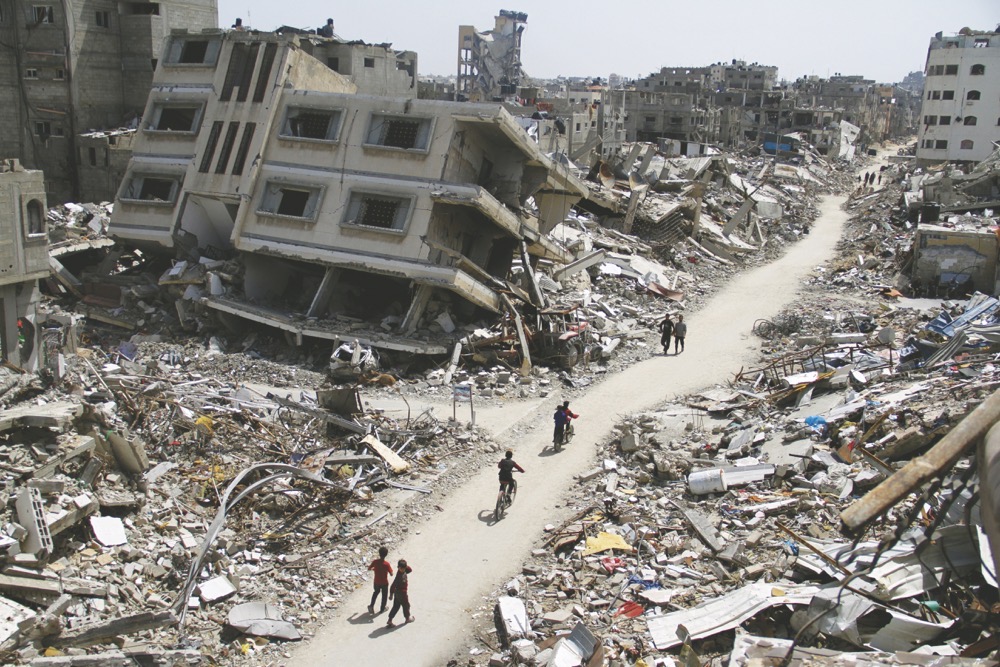 Palestinians ride bicycles past the ruins of houses and buildings destroyed by Israeli forces in the northern Gaza Strip. (Reuters)