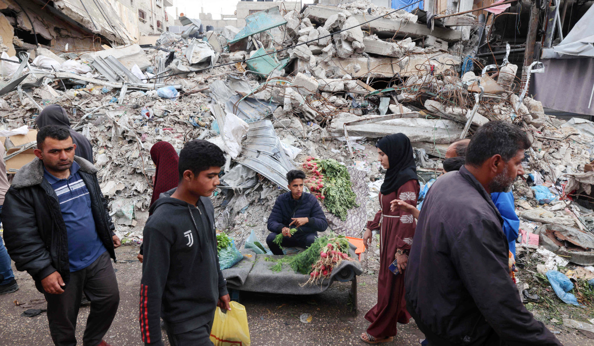 A Palestinian man sells fresh vegetables in front of a building destroyed by Israeli strikes in Rafah, southern Gaza Strip, amid the ongoing conflict between Israel and Hamas on Sunday. (AFP)