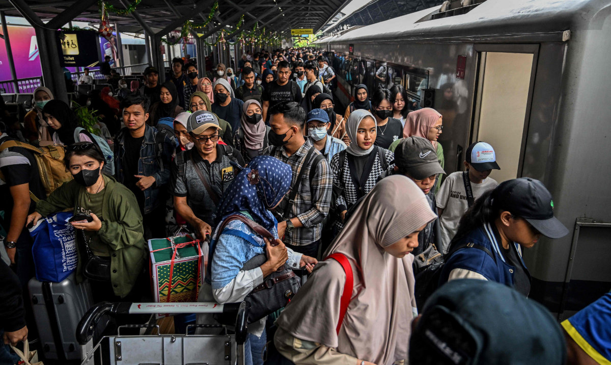 Passengers prepare to board a train for their long distance train to return home ahead of Eid Al-Fitr, which marks the end of the Muslim fasting month of Ramadan, at Gubeng station in Surabaya on April 7, 2024. (AFP)