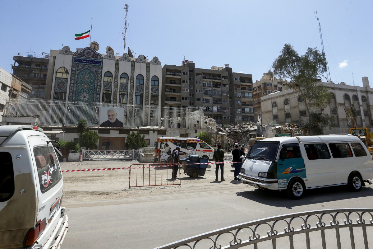 Vahicles drive past the cordoned-off Iranian Embassy building as workers remove the rubble of a consular annex a day after it was hit in a strike in Damascus on April 2, 2024(AFP)