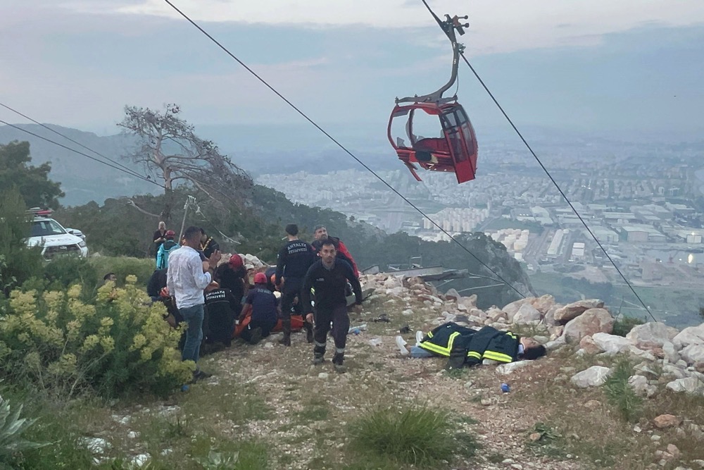 This handout photograph taken and released on April 12, 2024 by Turkish news agency DHA (Demiroren News Agency) shows rescue teams conducting a rescue operation and helping injured people after a cable car cabin crashed into a fallen cable pole in Konyaalti district of Antalya. (DEMIROREN NEWS AGENCY/AFP)