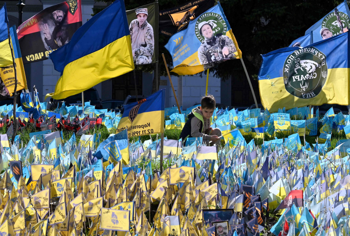 A boy sets a flag at a makeshift memorial for fallen Ukrainian soldiers at Independence Square in Kyiv on April 9, 2024, amid Russia's invasion on Ukraine. (AFP)