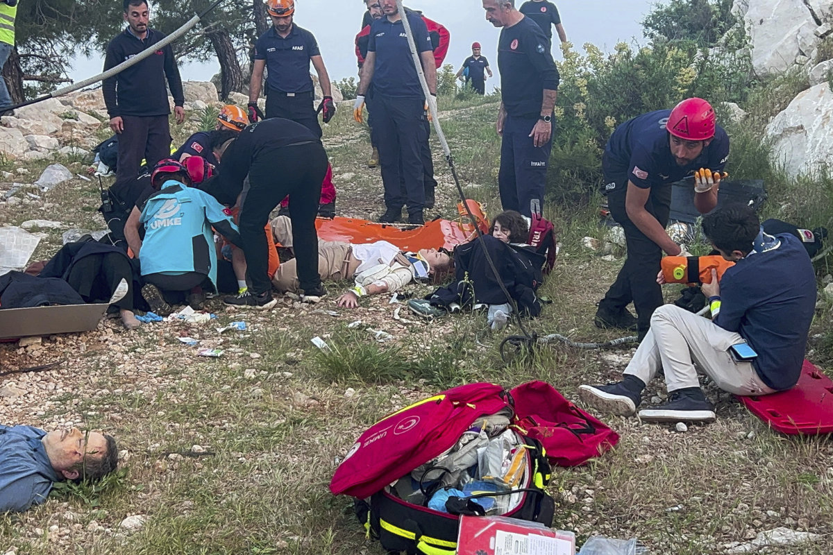 Rescue and emergency team members work with passengers of a cable car transportation system outside Antalya, southern Turkiye, on April 12, 2024. Scores of other people left stranded late into the night after the entire cable car system came to a standstill were rescued on Saturday. (Dia Images via AP)