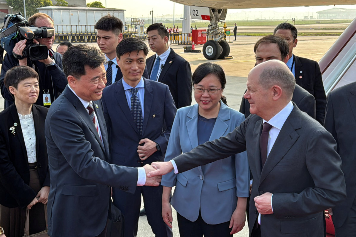 German Chancellor Olaf Scholz shakes hands with Chinese Ambassador to Germany Wu Ken next to Chongqing Vice Mayor Zhang Guozhi, upon arriving at the airport in Chongqing, China, on April 14, 2024. (REUTERS)