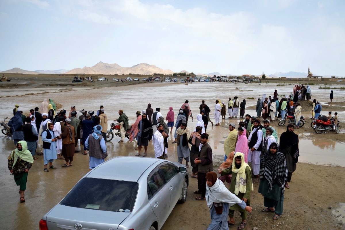 Afghans wait to cross a flooded area in Spin Boldak district of Kandahar province on April 13, 2024, after a flash flood following a heavy rainfall. (AFP)