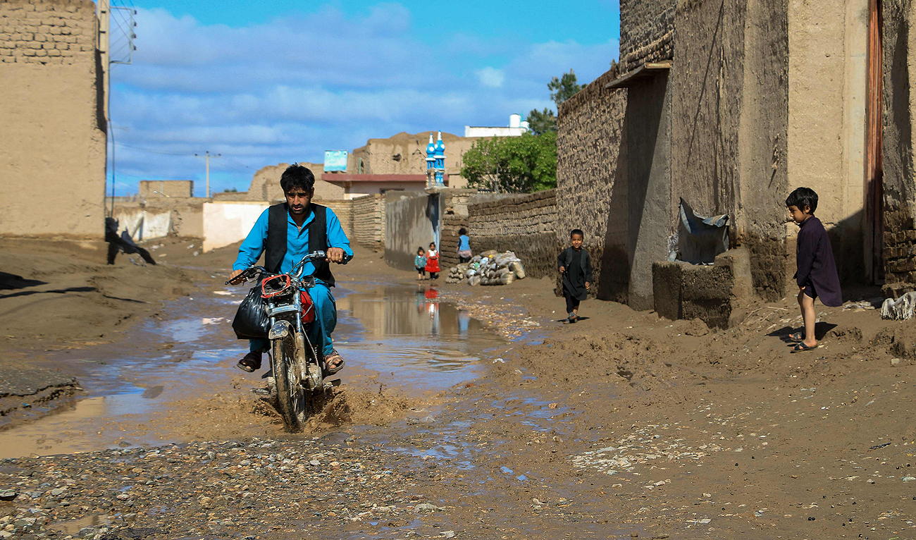 An Afghan motorist wades through a puddle following heavy rains and flash flooding in Guzara district of Herat province on April 15, 2024. (AFP)