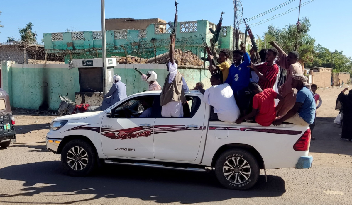 Armed Sudanese civilians wave weapons and chant slogans as they drive through the streets of Gedaref city in eastern Sudan on January 1, 2024 to express their support for the Army. (AFP)