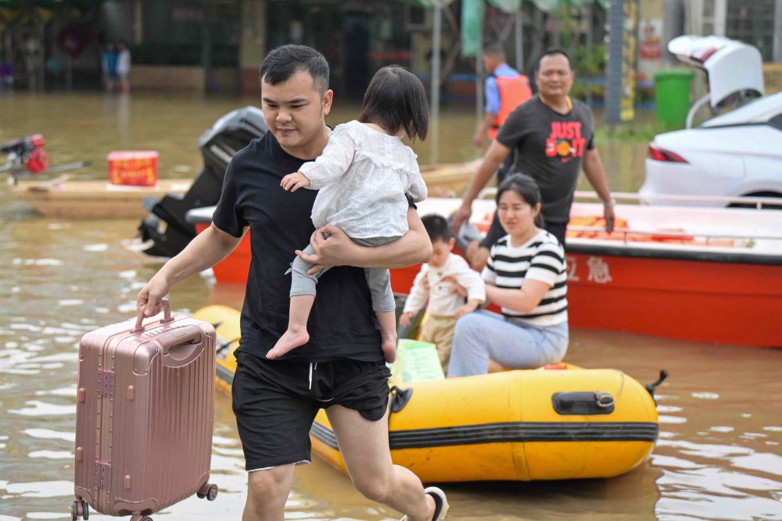Residents wade through floodwaters after being evacuated from a flooded area following heavy rains in Qingyuan city, in China’s southern Guangdong province. (AFP)