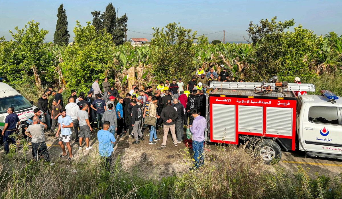 People gather at the site of an Israeli strike on a vehicle in the Adloun plain area, between Lebanon's southern cities of Sidon and Tyre, on April 23, 2024. (AFP)