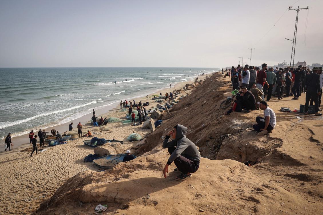 Palestinians watch fishermen returning at the beach next to a camp for the internally displaced in Rafah in the southern Gaza Strip on April 23, 2024. (AFP)