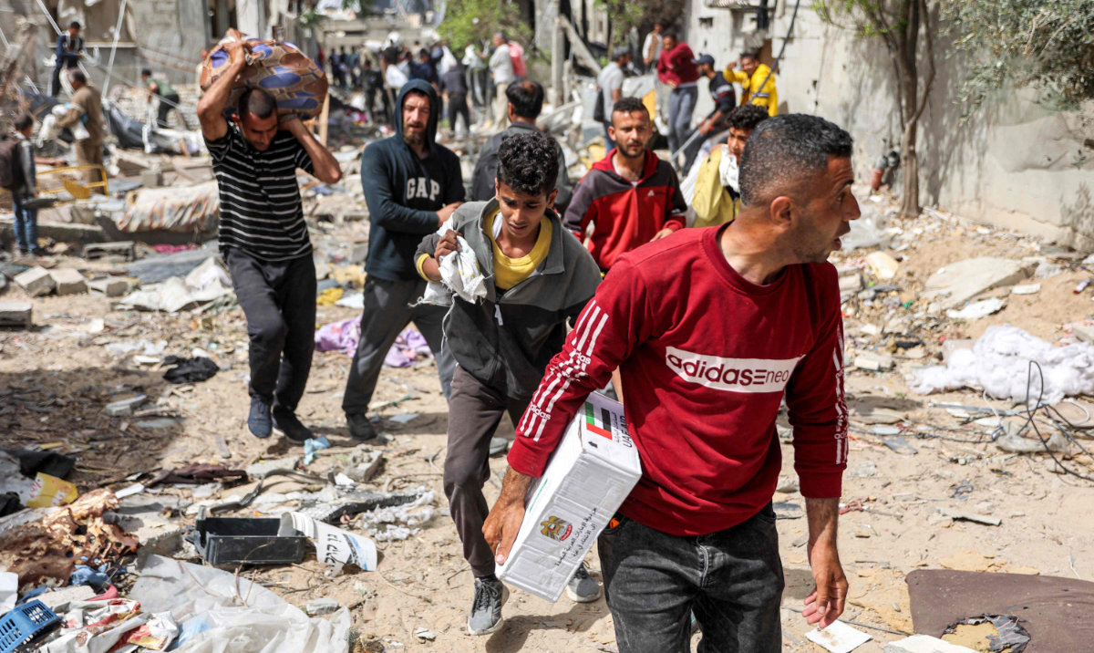 People walk through rubble past damaged buildings with humanitarian aid packages collected from a drop over the northern Gaza Strip on April 23, 2024 amid the ongoing conflict in the Palestinian territory between Israel and the militant group Hamas. (AFP)