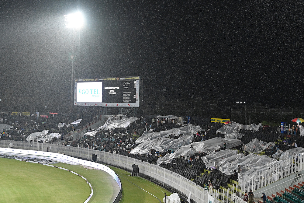 Spectators sit under plastic sheets as the match between Pakistan and New Zealand during their Twenty20 international at the Rawalpindi Cricket Stadium on April 18, 2024 was stopped due to rain. (AFP)
