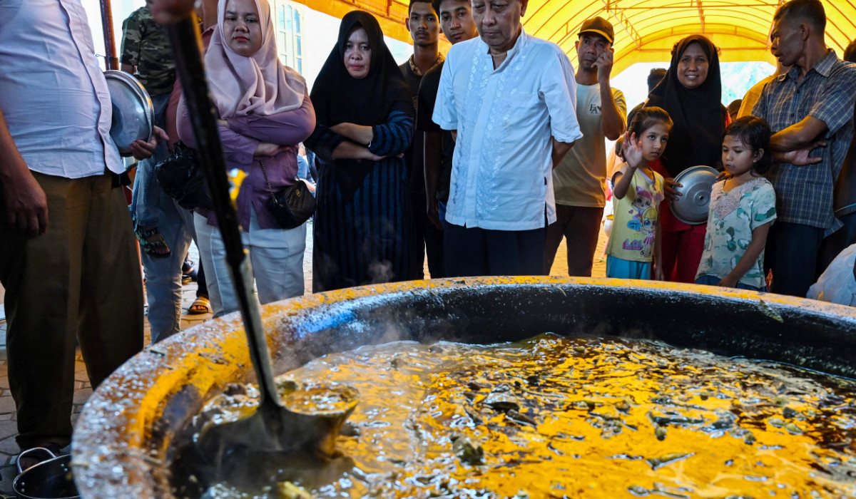 People look on as they wait to collect traditional curry dishes during Ramadan in Banda Aceh. (AFP)