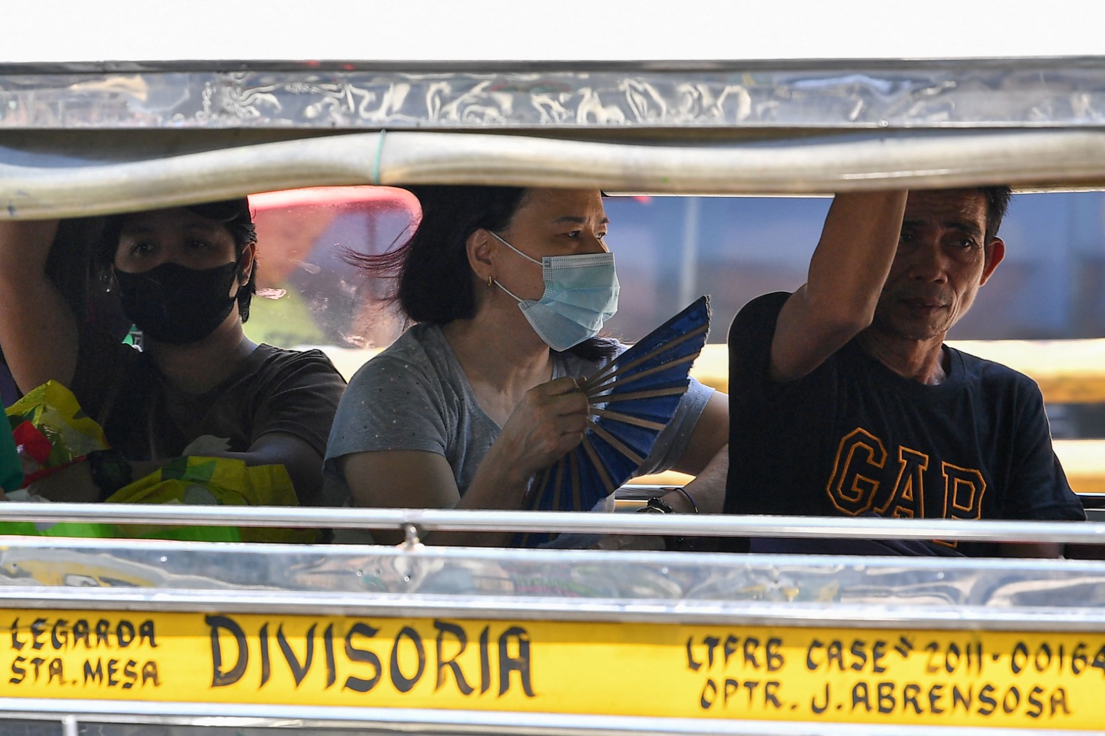 A woman cools off with a folding hand fan inside a passenger jeepney in Manila on April 25, 2024. (AFP)