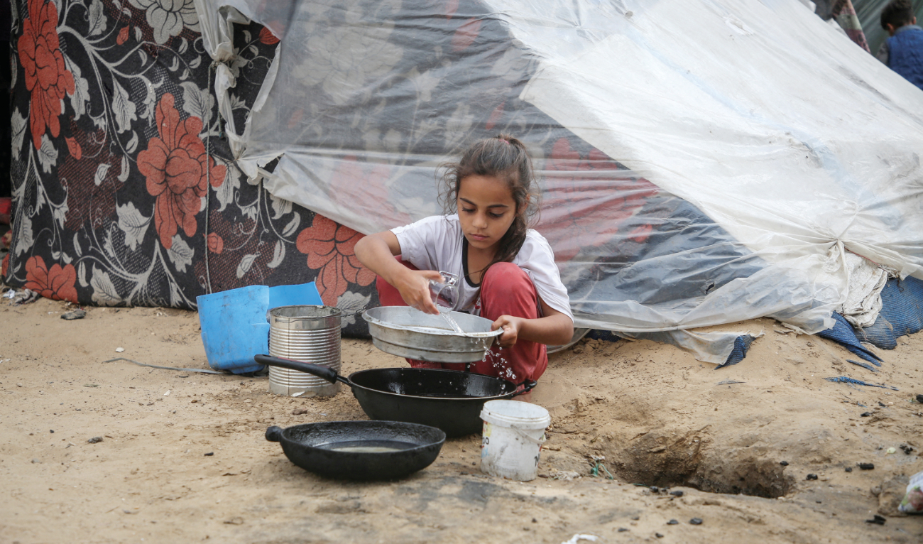 A girl pours water next to a tent in Rafah in the southern Gaza Strip amid the ongoing conflict between Israel and Palestinians. (Reuters)