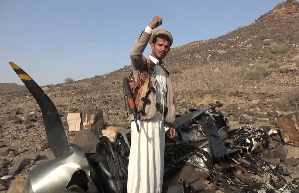 A Houthi fighter celebrates in front of what is alleged to be the debris of an American MQ9 aerial vehicle, claimed to have been shot down in Saada, Yemen, Friday, April, 26, 2024. (AP Photo)
