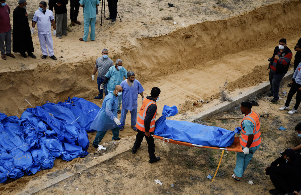 The bodies of Palestinians killed in Israeli strikes are buried in a mass grave, after they were transported from Al-Shifa hospital in Gaza City for burial, in Khan Younis, the southern Gaza Strip. (File/Reuters)