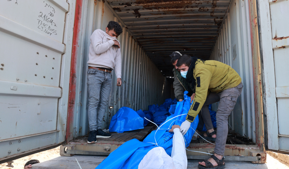 Gaza-based Palestinian Health Ministry workers prepare to bury the bodies of unidentified Palestinians whose date of death is not known after they were returned by Israel earlier on the same day through the Kerem Shalom crossing, at a mass grave east of Rafah in the southern Gaza Strip on January 30, 2024. (AFP)