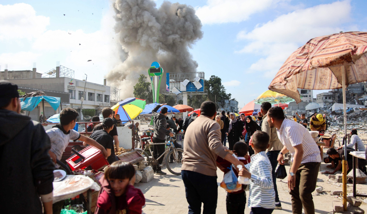 Palestinians look at smoke billowing during Israeli bombardment on the Firas market area in Gaza City on April 11, 2024. (AFP)