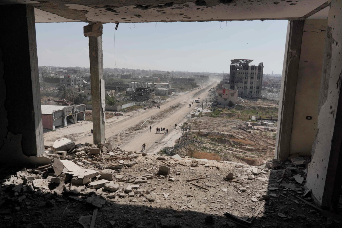 People walk past the ravaged building of Al-Salam hospital (R) in Khan Yunis on April 7, 2024. (AFP)