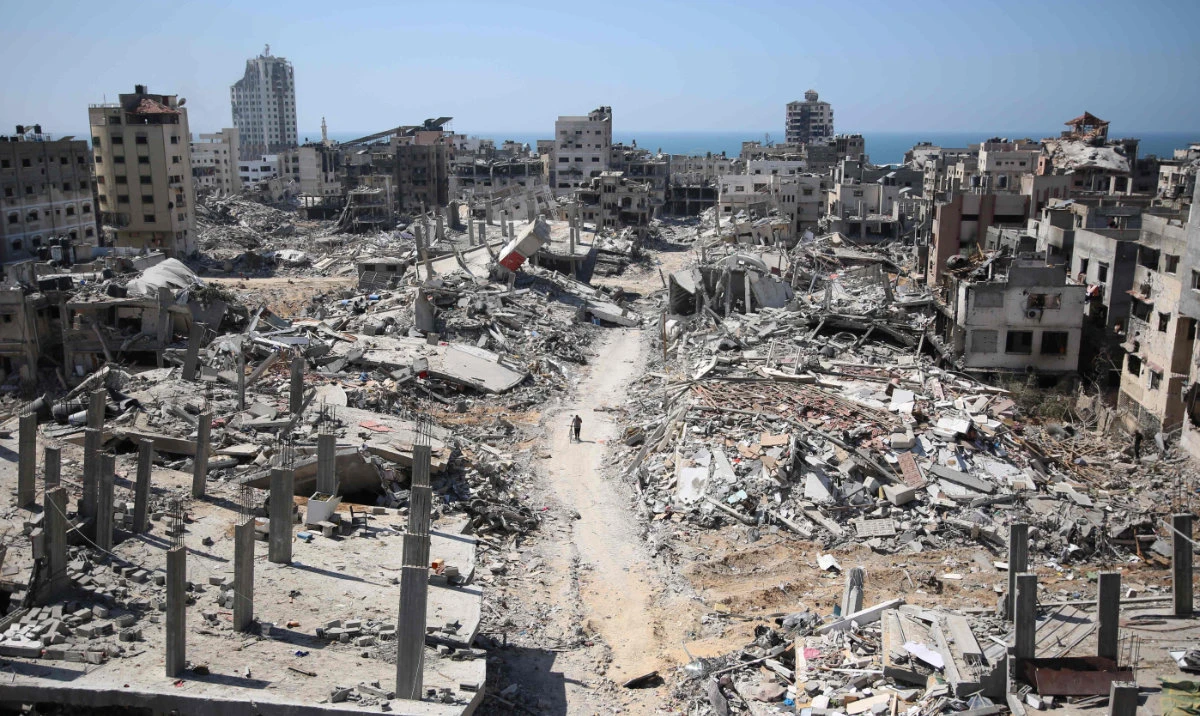 A man pushes a bycicle along as he walks amid building rubble in the devastated area around Gaza's Al-Shifa hospital on April 3, 2024. (AFP)