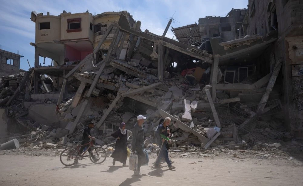 Palestinians walk through the destruction in the wake of an Israeli air and ground offensive in Khan Younis, southern Gaza Strip, Monday, April 8, 2024. (AP Photo)