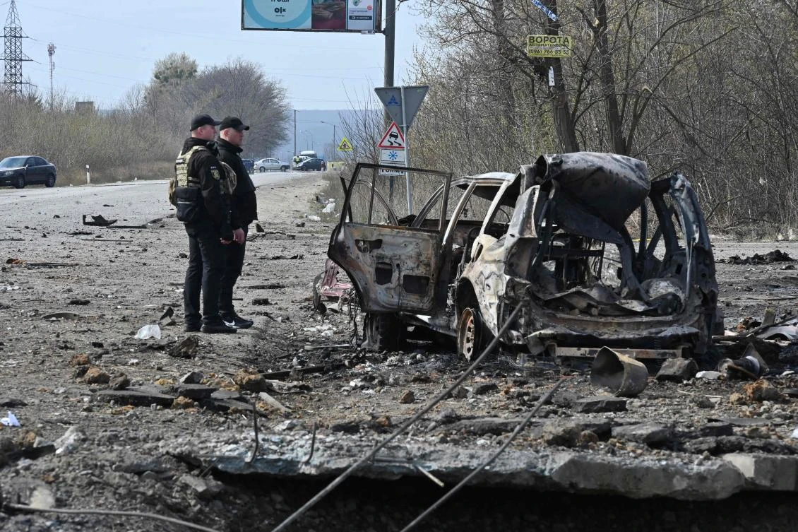 Policemen examine a destroyed car after missiles strike in Kharkiv, on Apr. 6, 2024. (AFP)