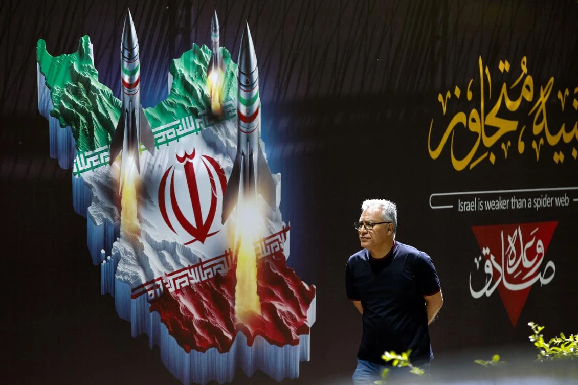 Above, a man walks past a banner depicting missiles along a street in Tehran on April 19, 2024.(AFP)