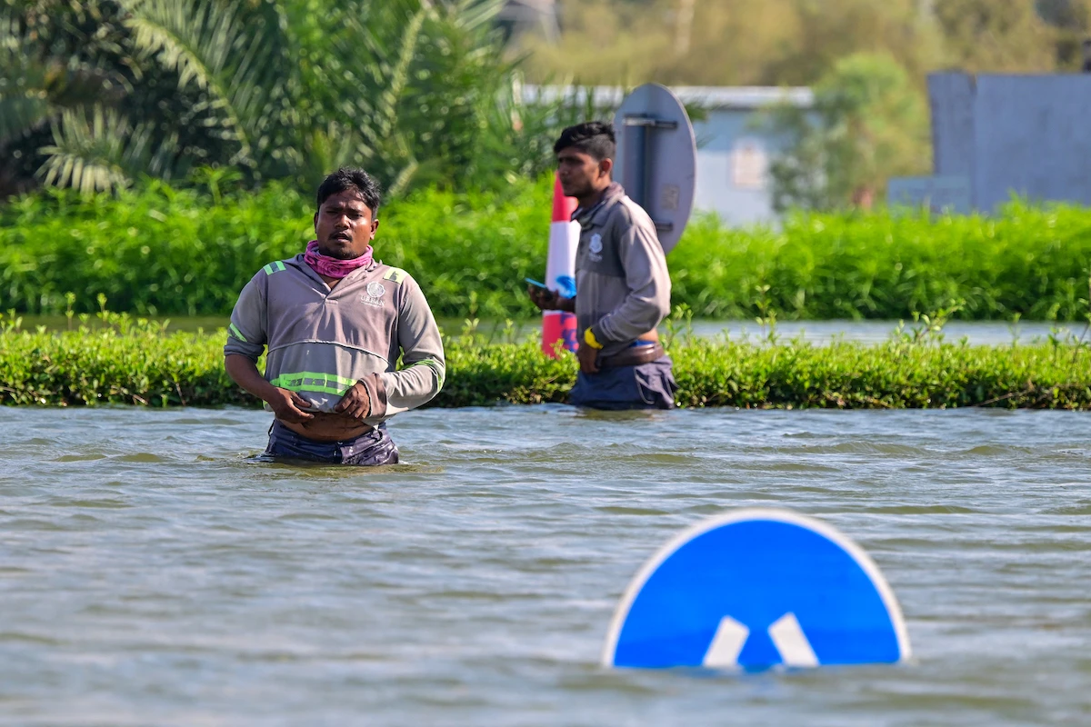 People wade through water in a flooded street in Dubai on April 19, 2024. (AFP)