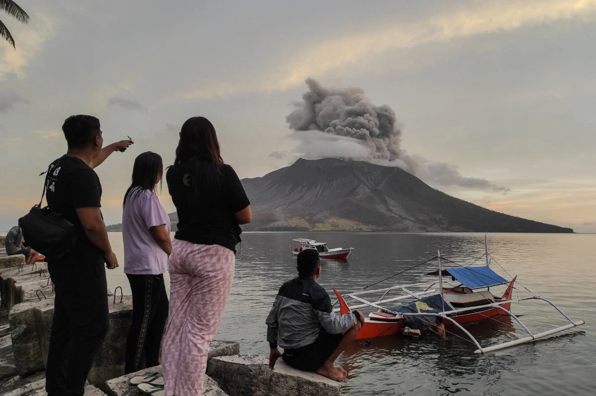 People watch from Tagulandang Island in Sitaro, North Sulawesi, as Mount Ruang volcano spews volcanic ash on April 19, 2024. (AFP)