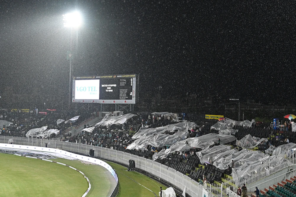 Spectators sit under plastic sheets as the match between Pakistan and New Zealand during their Twenty20 international at the Rawalpindi Cricket Stadium on April 18, 2024 was stopped due to rain. (AFP)