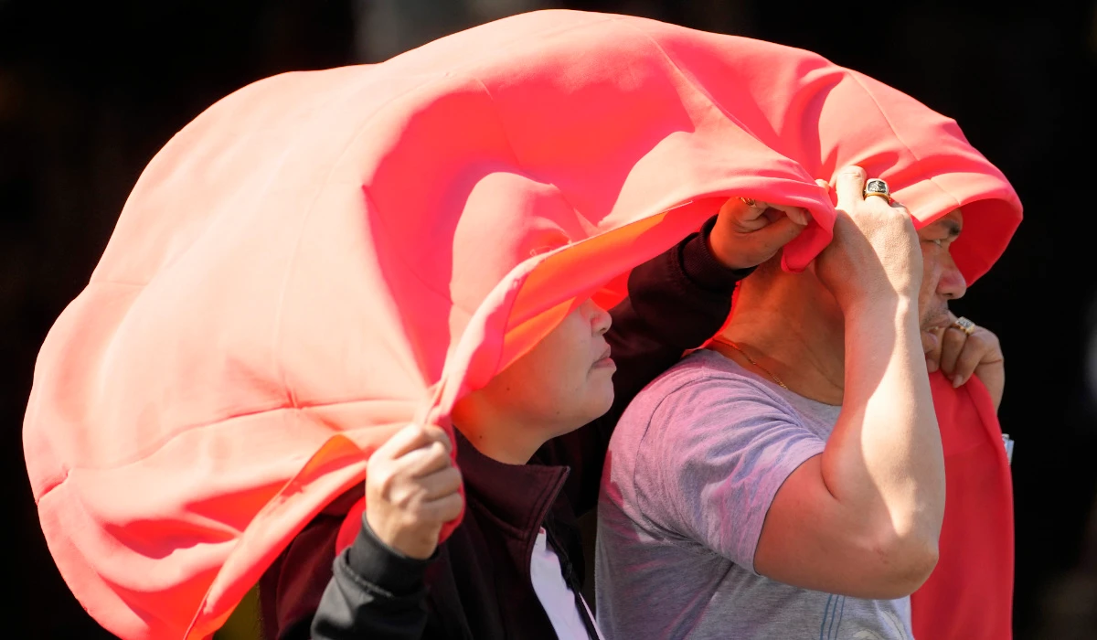 A man and woman use a cloth over their heads to protect them from the sun in Manila, Philippines on Monday, April 29, 2024. (AP)