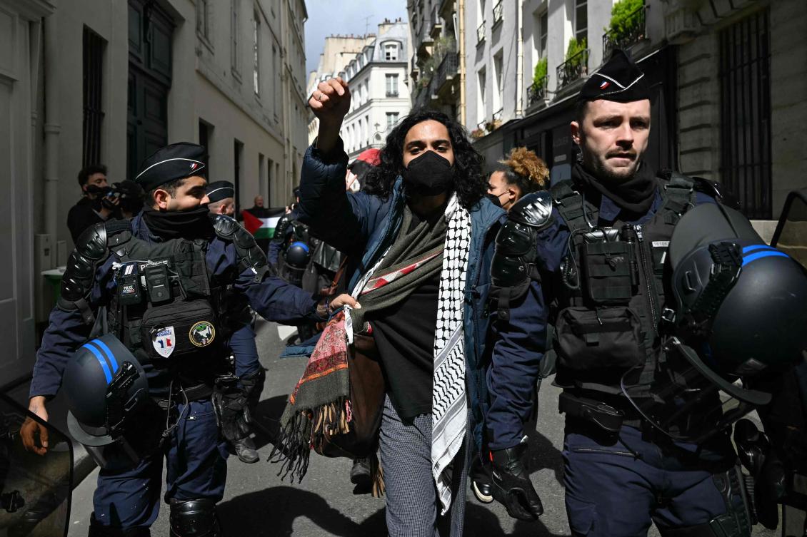 A protester is escorted away by French gendarmes during the evacuation of a pro-Gaza sit-in in the entrance hall of the Institute of Political Studies (Sciences Po Paris) in Paris. (AFP)