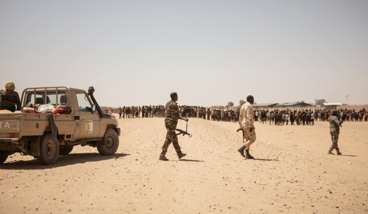 Soldiers of the Niger Armed Forces are seen as a crowd of migrants gather in Assamaka, Niger, on March 29, 2023. (AFP)