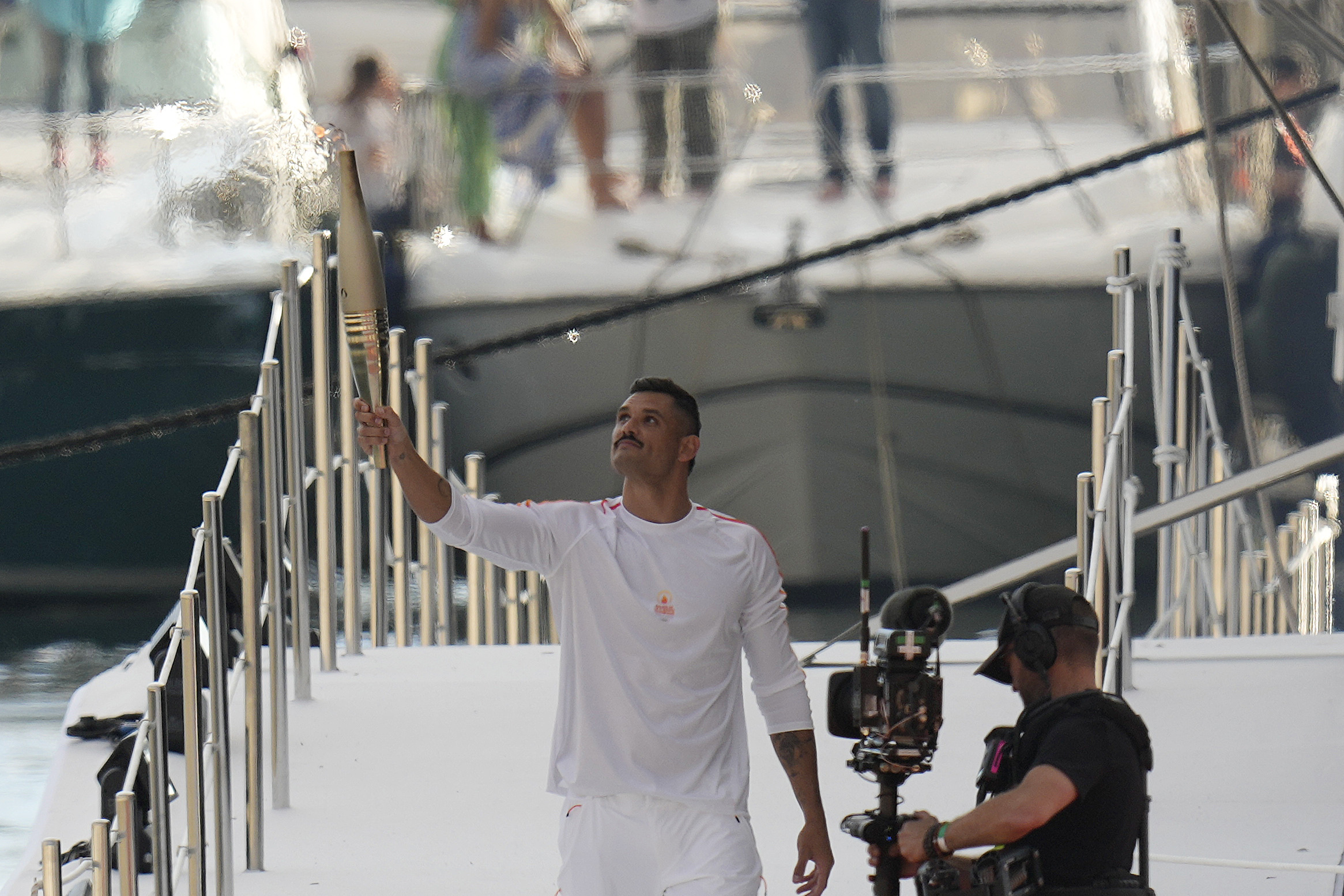 First torch carrier in France French Olympic swimmer Florent Manaudou holds the Olympic torch after leaving The Belem, the three-masted sailing ship in the old port of Marseille, southern France. (AP)