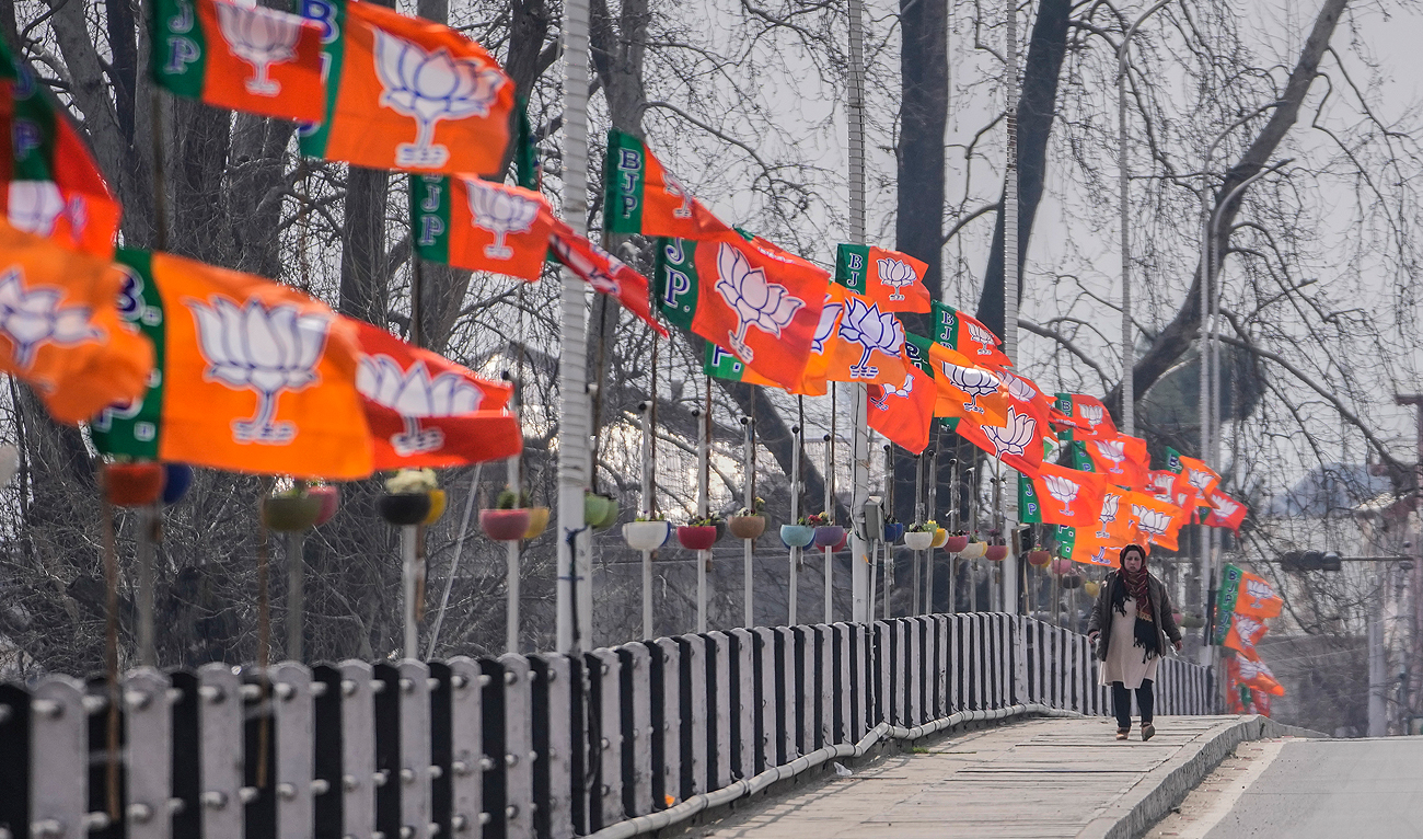 A woman walks past India’s ruling Bharatiya Janata Party (BJP) party flags displayed ahead of the Indian Prime Minister Narendra Modi’s visit to Srinagar, Indian administered Kashmir, on March 6, 2024. (AP)
