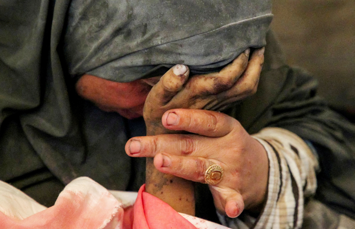 Palestinian woman Buthayna Abu Jazar reacts as she holds the hand of her son Hazma, who was killed in an Israeli strike, amid the ongoing conflict between Israel and Hamas, in Rafah, in the southern Gaza Strip May 9, 2024. (REUTERS)