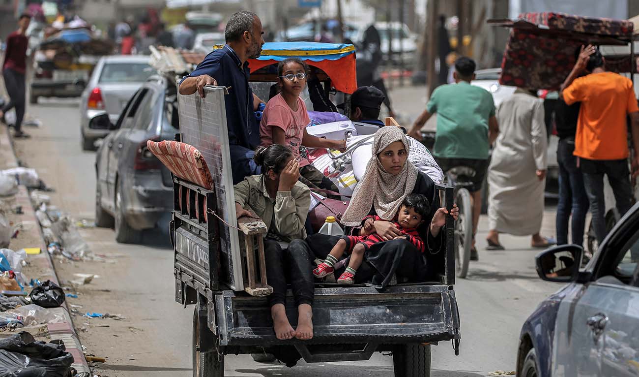 A man, woman, and children ride in the back of a tricycle loaded with belongings and other items as they flee bound for Khan Yunis, in Rafah in the southern Gaza Strip on May 11, 2024 amid the ongoing conflict in the Palestinian territory between Israel and Hamas. (AFP)