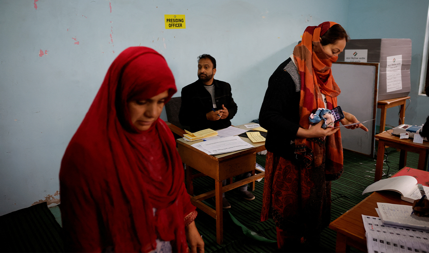 Election officers check the identity proof of voters at a polling station, during the fourth general election phase, in south Kashmir's Pulwama district, on May 13, 2024. (AFP)