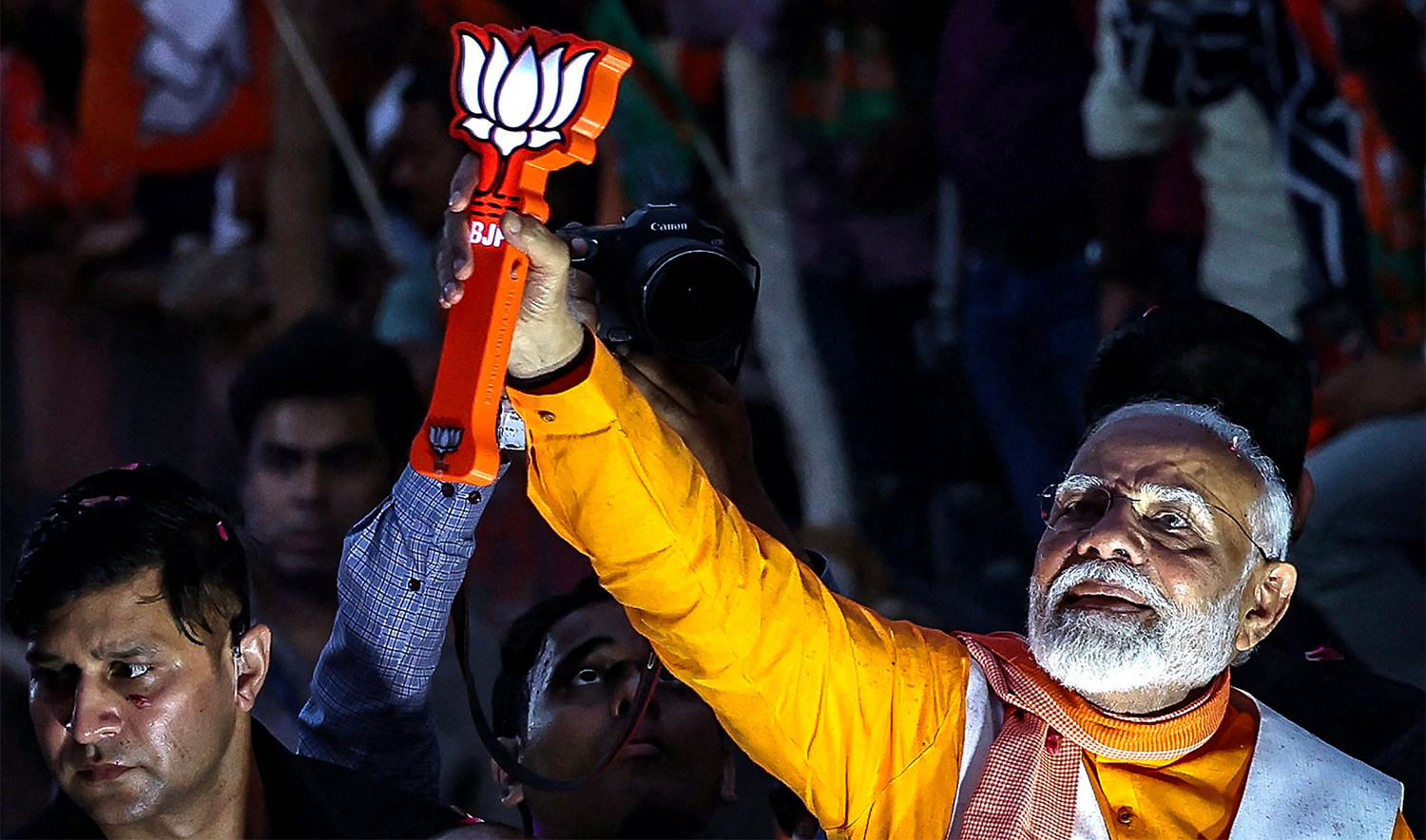 India's Prime Minister and leader of the ruling Bharatiya Janata Party (BJP) Narendra Modi (R) greets his supporters as he takes part in a roadshow on the eve of filing of his election nomination papers, in Varanasi on May 13, 2024, during ongoing India's general election. (AFP)