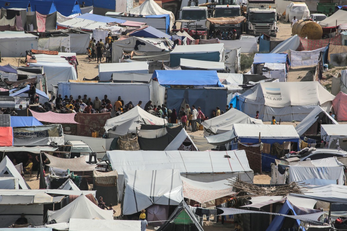 alestinians line up to receive humanitarian aid amidst tents housing internally displaced people, along the coastline in Deir el-Balah in the central Gaza Strip on May 10, 2024, amid the ongoing conflict between Israel and the militant group Hamas (AFP)
