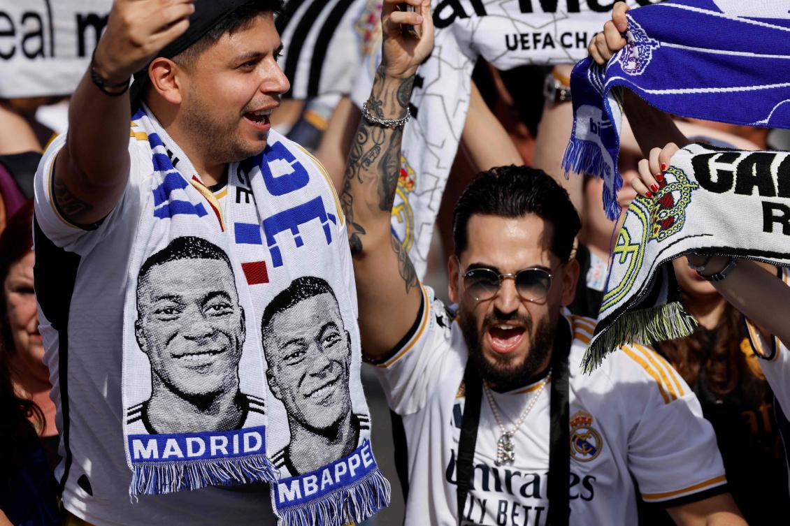 Supporters wearing football scarves depicting French footballer Kylian Mbappe cheer prior Real Madrid’s celebration for winning 2024 Spanish Liga title at Cibeles square in Madrid on May 12, 2024. (AFP)