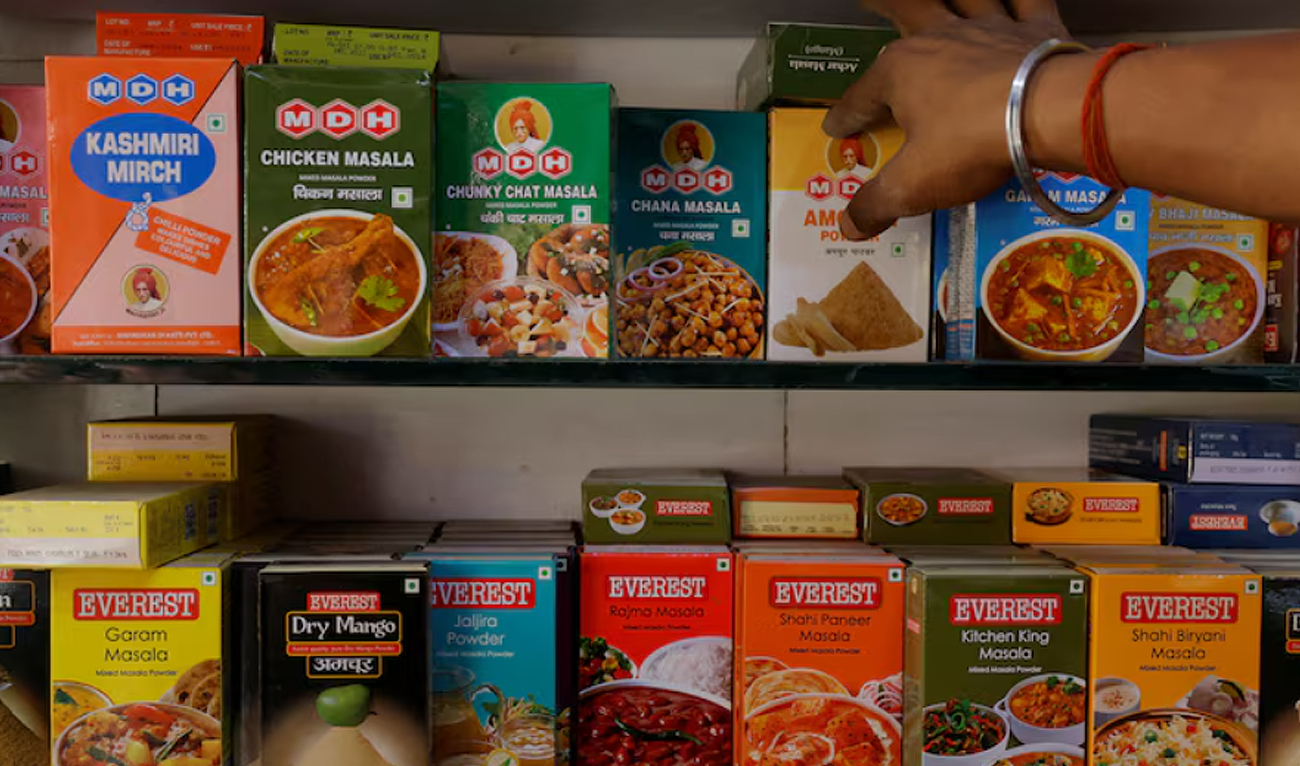 A man adjusts the spice boxes of MDH and Everest on the shelf of a shop at a market in New Delhi, India, April 29, 2024. (REUTERS)