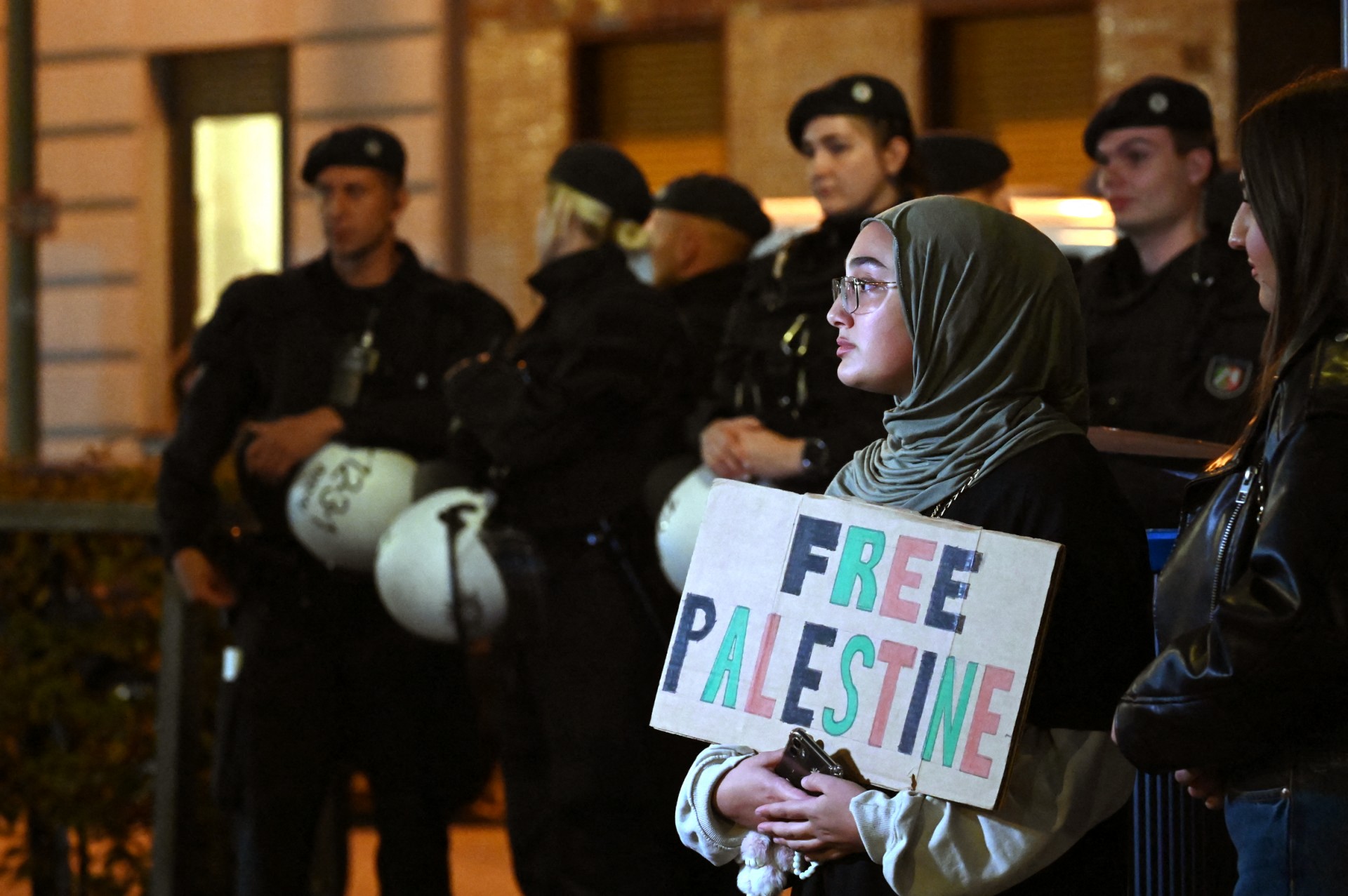 A pro-Palestine demonstrator holds up a placard in front of police officers during a "in solidarity with Gaza" rally in Duisburg, western Germany (AFP)